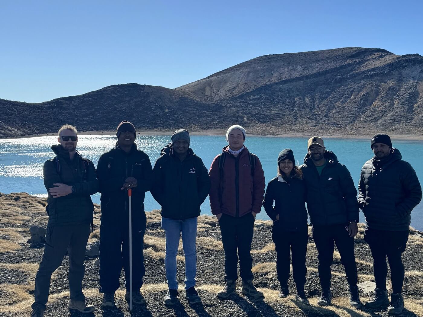 Seven members of the Nash NZ team on the Tongariro Alpine Crossing, standing beside the Blue Lake.
